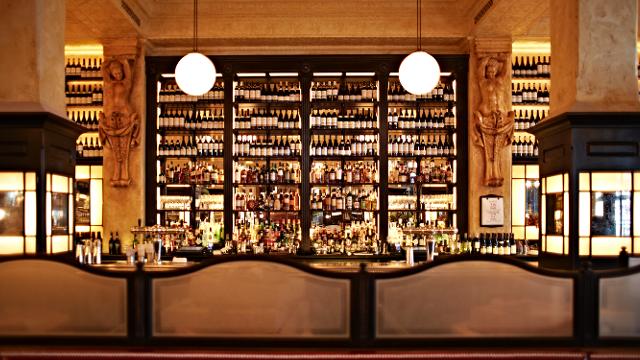 Balthazar brings a taste of New York to Covent Garden. Image courtesy of Balthazar London. A yellow-lit bar with bottles lining the back wall at balthazar london.