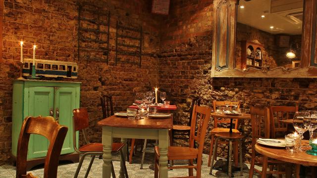 The cosy, rustic dining room at French restaurant Blanchette, with wooden tables, wooden chairs, brick walls and candles.
