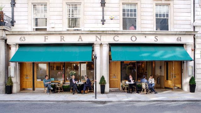 Franco's Italian restaurant in London. Image courtesy of Franco's. Landscape photo of the outside of Franco's - gold decor and green awnings outside the window