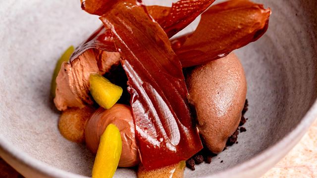Shards of milk chocolate, chocolate ice cream and yellow fruit, assembled creatively in a bowl at Hélène Darroze at The Connaught.