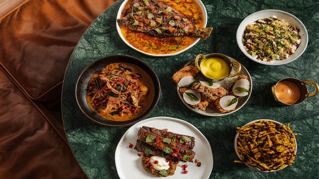 Indian inspired dishes at Kricket. © Kricket/Rebecca Hope high angle shot of 5 white bowls varying in size with authentic Indian cuisine including curry, on a dark green round table