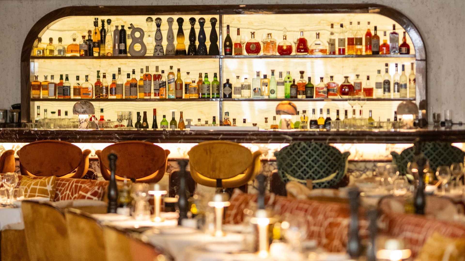 Discover the glamour of the French Riviera in the heart of Knightsbridge at La Môme London. Image courtesy of Bacchus Agency. A warmly lit bar in la mome restaurant with plush furniture.