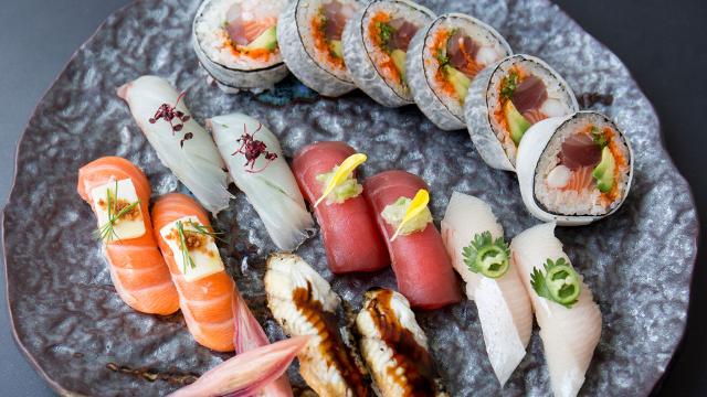 Colourful nigiri and maki sushi laid out on a grey plate.