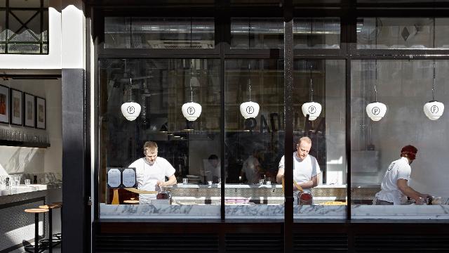 Three chefs make pasta in the window of padella restaurant in borough market in london.