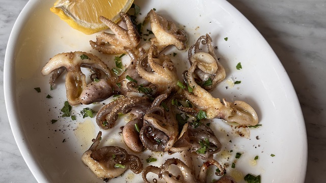 Venetian cuisine with a twist at Polpo. Image courtesy of Polpo. Birds eye view shot of a white oval plate with cooked baby octopus and a wedge of lemon