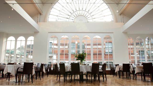 Tables in a large restaurant with big a high ceiling and large.