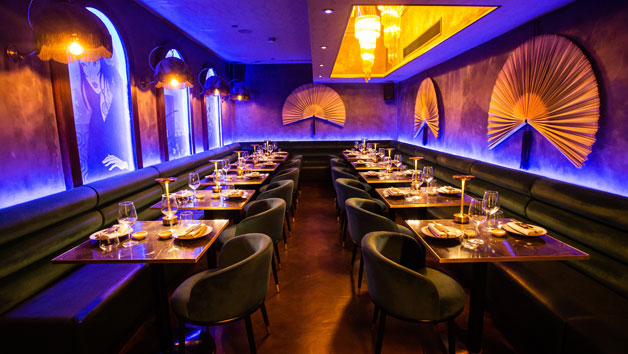 A purple restaurant dining space with black tables and wide yellow fans on the wall. 