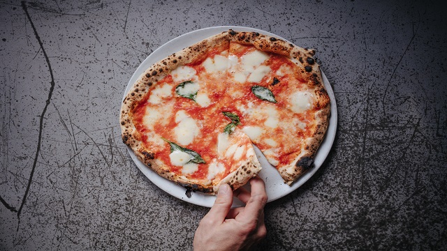 Margherita pizza at Sodo. © Sodo/Jon Attenborough High angle shot of a large Margherita pizza, with a hand taking a slice