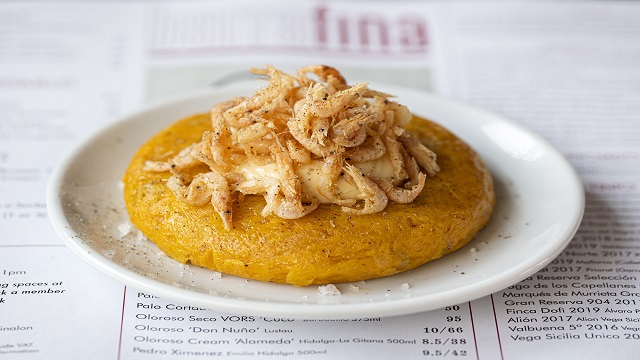 Diner-style tapas bar Barrafina serving Spanish small plates. © Barrafina/John Carey a small white plate with a tortilla topped with shrimps