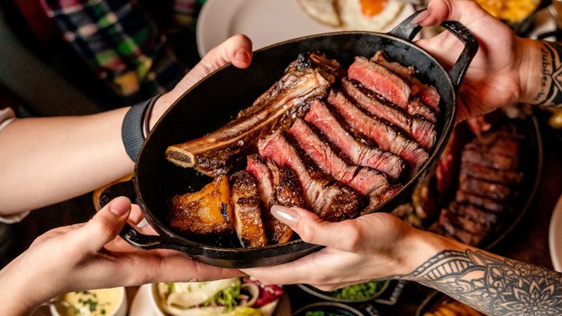 Grab some mates and get the sharing steak at Hawksmoor, you won't regret it! Credit: Hawksmoor. Image courtesy of Hawksmoor. A bird's-eye photo of the sharing steak at Hawksmoor with a pair of hands passing the dish over to another pair of hands