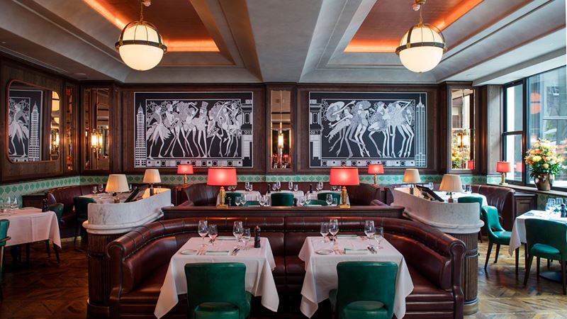 Tuck into steak from across the pond at Smith & Wollensky. Credit: Smith & Wollensky. Image courtesy of Smith & Wollensky. A photo of the interior of Smith & Wollensky with wooden furniture, white tablecloths and warm overhead lighting