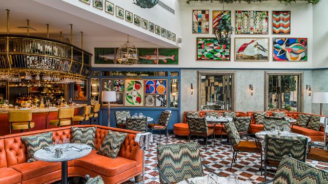 The Ivy Tower Bridge. Image courtesy of The Ivy. The jazzy interiors of the ivy tower bridge, with bright tiles, paintings on the walls and orange sofas.