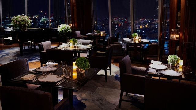 TING restaurant at Shangri-La. Image courtesy of TING restaurant. A low-lit restaurant with leather chairs and candles on brown tables.