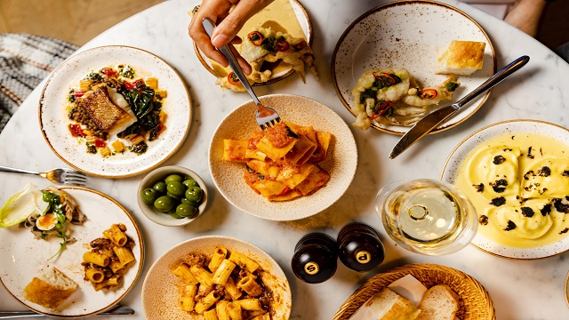Venetian-inspired Italian dishes at Tozi. © Tozi/Joe Howard Birdseye shot of small plates of Italian pasta and side dishes with a person tucking into one of the plates