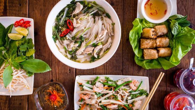 An array of Vietnamese dishes including spring rolls, noodle soup and a prawn and vegetables dish.