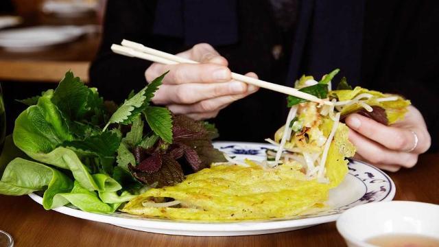 Person preparing a Vietnamese roll with salad, vegetables and meat.