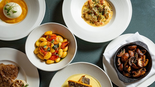 aerial landscape shot of 6 white bowls varying in size, with food presented inside including seabass, burrata and gnocchi