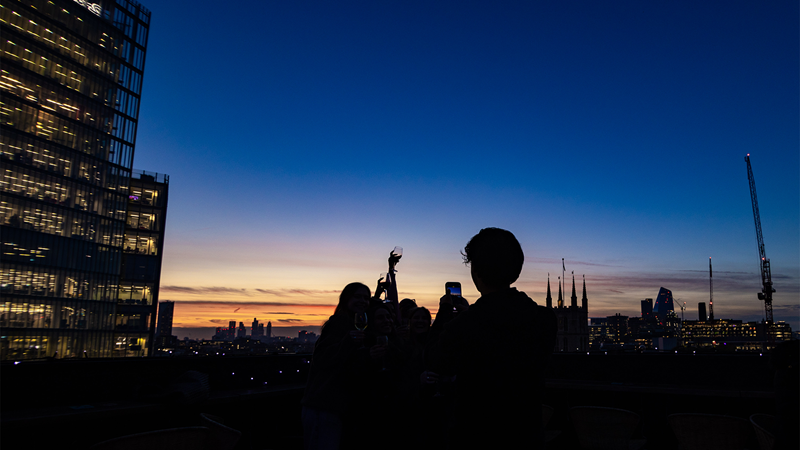Admire beautiful sunset skylines from London Bridge Rooftop. Credit: Daniel Mckenzie-Cossou. Image courtesy of We Are Indigo. A sunset skyline with shadows of people at London Bridge Rooftop bar