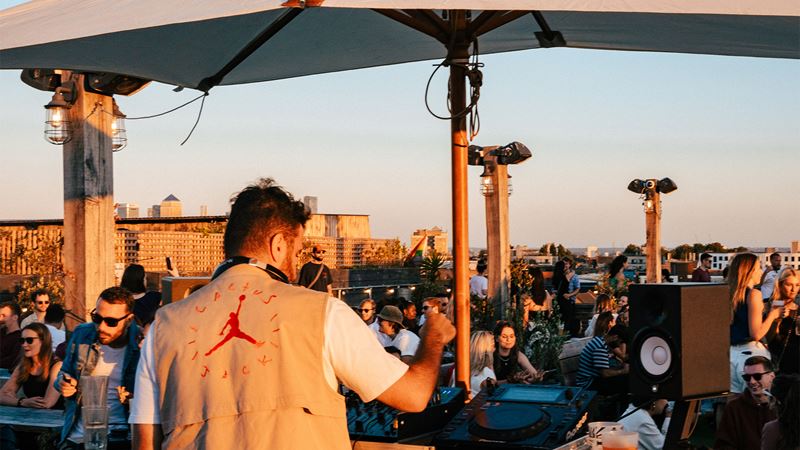 Dance the day away at east London's popular rooftop bar, Netil360. Credit: Reganography. Image courtesy of Netil360. A DJ infront of a crowd at the Netil360 rooftop bar.