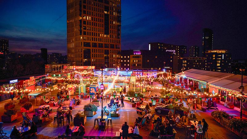 Have fun with friends at Stratford's epic rooftop playground, Roof East. Credit: Roof East. Image courtesy of Roof East. An evening aerial shot of Roof East's rooftop terrace and its neon lights
