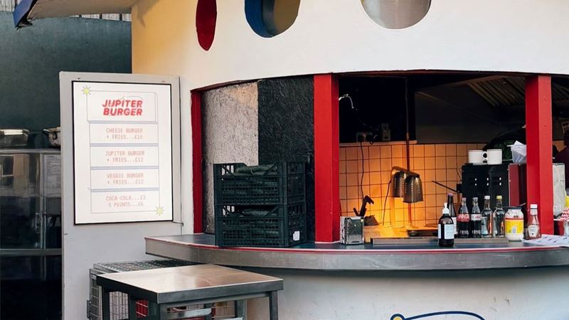 You can't go wrong with a juicy smash burger from Netil Market's Jupiter Burger. Credit: Potoczna. Image courtesy of Jupiter Burger. A photo of the spaceship-inspired Jupiter Burger stand at Netil Market with the menu on the wall and silver bar stools at the counter