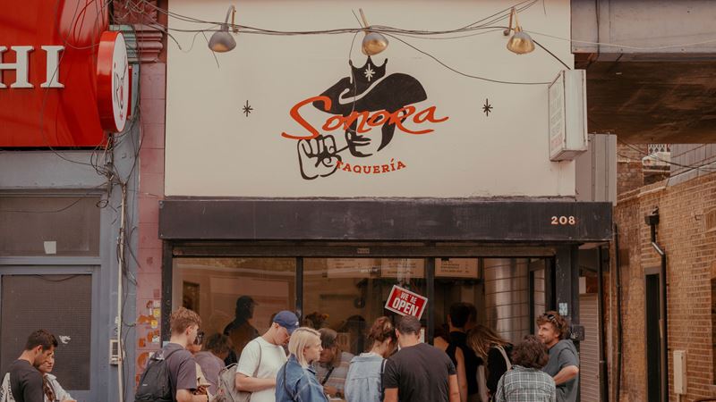Chow down on juicy meats encased in toasted corn tortillas at Sonora Taqueria in Stoke Newington. Credit: Paola Vivas. Image courtesy of Sonora Taqueria. A photo of the exterior of Sonora Taqueria in Stoke Newington with a queue of people outside