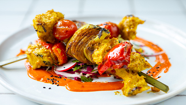 Close up on a plate served at Mildred's, the vegetarian restaurant, presenting two vegetarian kebab skewers.