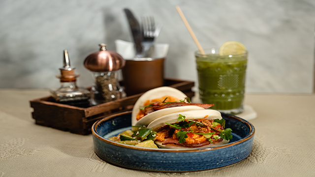 A plate of  warm and fluffy bao buns, filled with crispy onions and smacked cucumbers.
