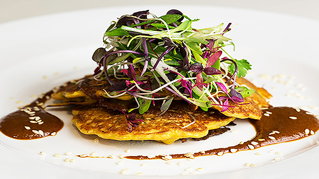 Plate of savoury pancakes topped with a mixed salad.