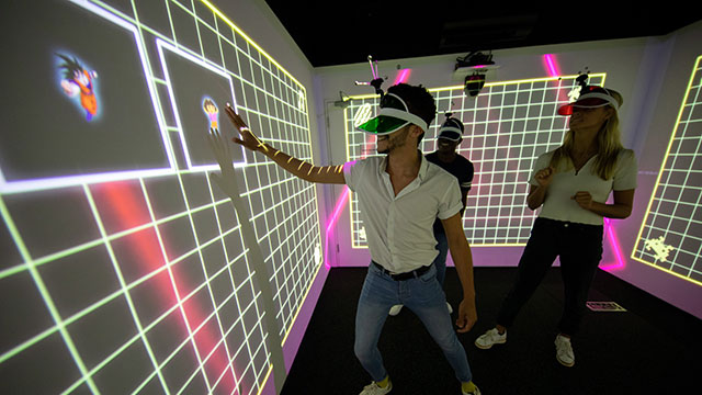 Get together with friends at Electric Gamebox for an immersive gaming experience © Idea Farm. Image courtesy of Idea Farm. A male and female group in a multicoloured LightBox playing an interactive immersive game.