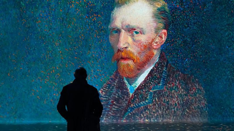 Get up close with the artists at the immersive FRAMELESS exhibition. Image courtesy of FRAMELESS. A man stands in a gallery in front of Van Gogh's self-portrait at the Frameless exhibition in London.