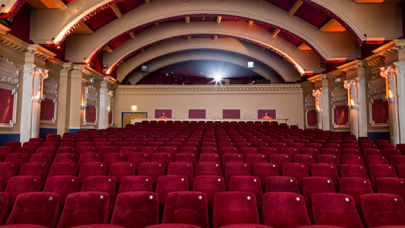 Rows of red velvet cinema seats with the arched ceiling above