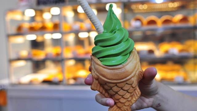 Hand holding taiyaki, a fish-shaped waffle filled with ice cream, in London Chinatown.