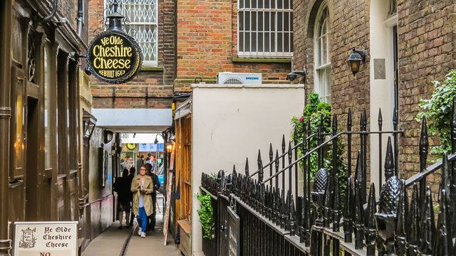 A cosy pub in London, Ye Olde Cheshire Cheese pub alleyway with a woman walking towards the pub's side entrance.