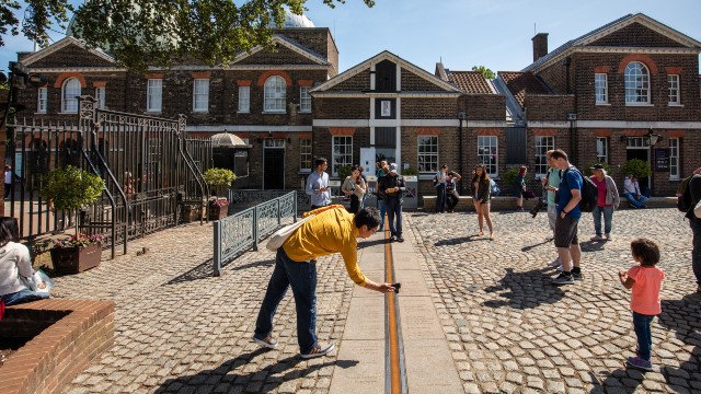 A man in a yellow top photographs the Prime Meridian line at Royal Observatory.