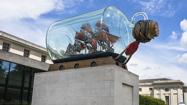 Replica of Nelson's ship inside a large glass bottle on a stone plinth. 