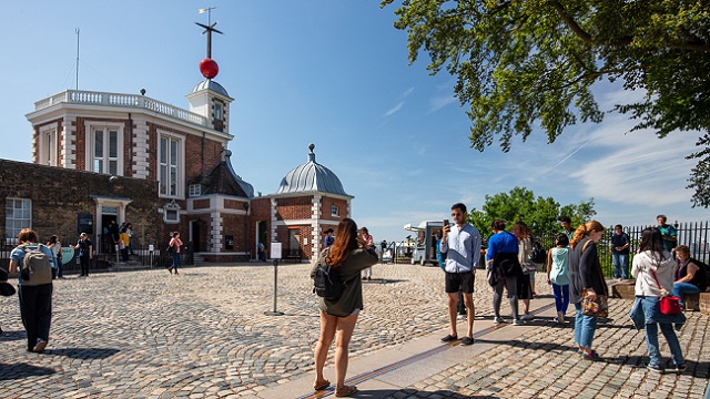 Explore the skies at the Royal Observatory Greenwich. Image courtesy of Visit Greenwich. People stand astride the Meridian Line outside the Royal Observatory Greenwich.
