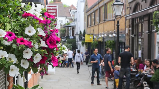 People walking and hanging out on a street in Hampstead, London.