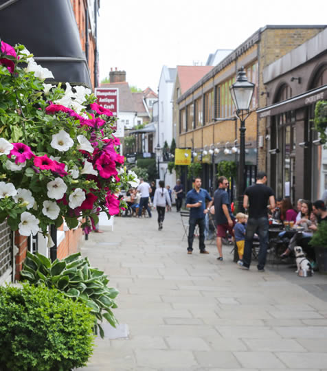 Hanging basket of flowers and people sitting outside a pub in Hampstead