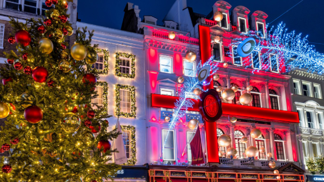 London West End buildings lit up with Christmas decorations, with a Christmas tree in the foreground.