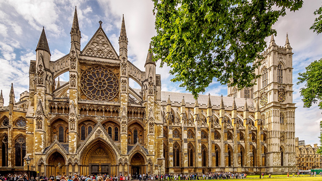 Westminster Abbey on a sunny day with trees in the foreground.