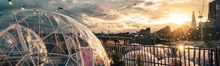 Dining igloos overlooking London's skyline at sunset.