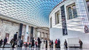 Visitors are walking within the Great Court at the British Museum and its blue dome.