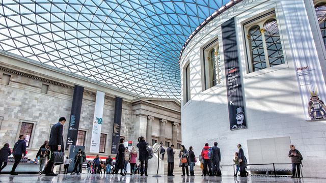 Visitors are walking within the Great Court at the British Museum and its blue dome.