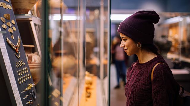 A young woman is admiring ancient jewellery exhibited at the British Museum.