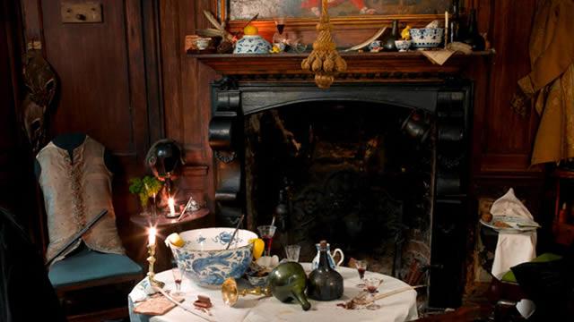 A table with crockery in front of a fireplace on the candlelight tour at dennis severs house.