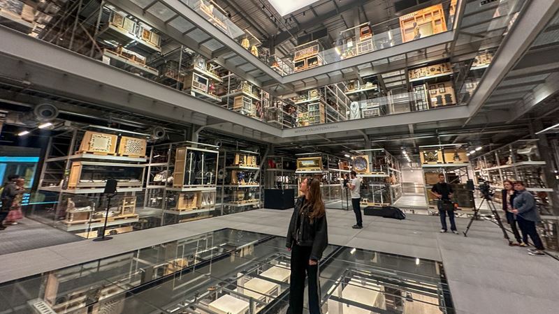 A woman stands in the grand hall of the v&a east storehouse in london surrounded by artefacts