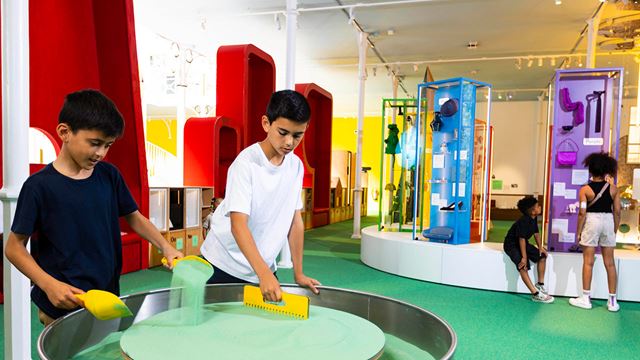 Two boys playing with green sand in a sand spinner