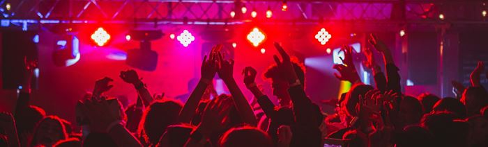 People dancing in a club with hands up in the air and red lights.