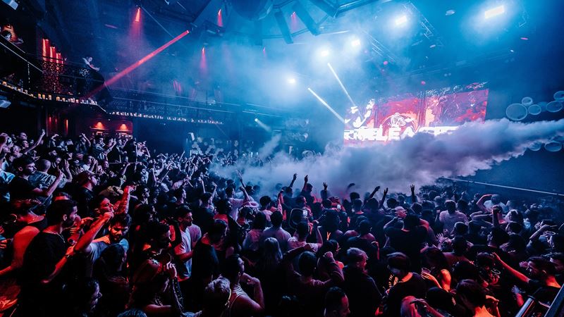 Experience world-class DJs, a state-of-the-art sound system and top club nights at Studio 338. Credit: Studio 338. Image courtesy of Studio 338. A huge crowd of partygoers dancing with arms up in the air at Studio 338 nightclub in London with blue and red lights.